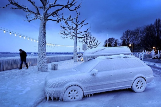 Мужчина проходит мимо покрытого льдом автомобиля. Снимок сделан у набережной в городе Версуа, недалеко от Женевы, Швейцария.