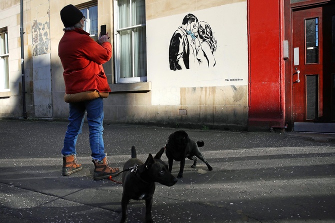 Шотландский уличный художник, который известен как Взбунтовавшийся Медведь, на одном из зданий в Глазго изобразил, как двое молодых людей, несмотря на все ограничения, продолжают любить и влюбляться.  Фото: Getty Images/PA Images/Andrew Milligan
