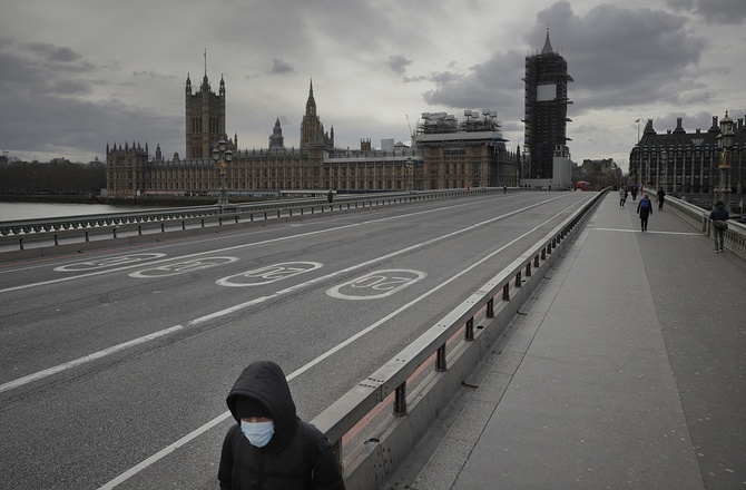 Человек в медицинской маске идет по пустому Вестминстерскому мосту, расположенному рядом со зданием парламента в центре Лондона. Лондон, 20 марта ©AP Photo/Matt Dunham