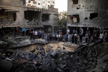 Палестинцы стоят вокруг кратера, образовавшегося в результате израильского авиаудара по дому в городе Газа. фото 6