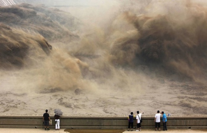 На фотографии изображены гости центральной китайской провинции Хэнань, наблюдающие за процессом предотвращения локализованного наводнения.