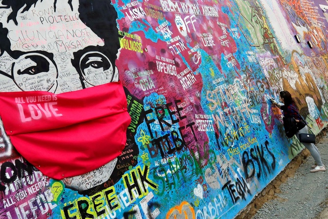 На легендарной стене Джона Леннона в Праге появились актуальные дополнения – кумира заботливо нарядили в маску, чтобы уберечь от вируса. Фото: REUTERS/David W Cerny