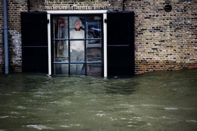 Житель города Дордрехт, Голландия, наблюдает за выском уровнем воды через окно своего дома.