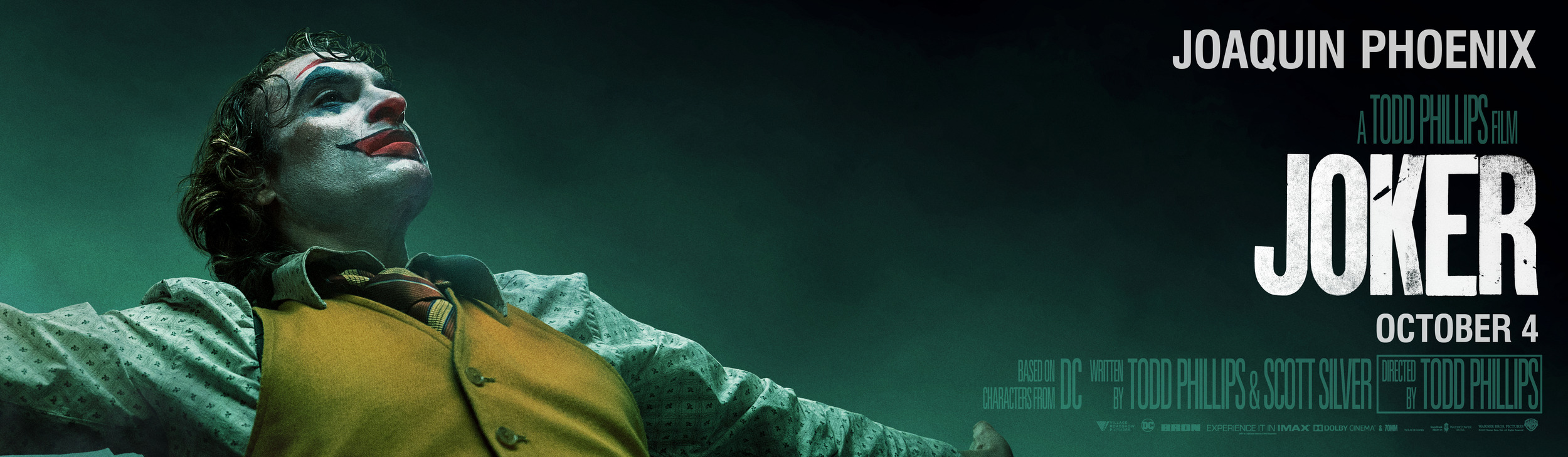 Хоакин Феникс делает счастливое лицо на баннере «Джокера»